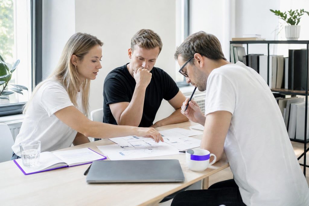 Three people discussing documents at a table.