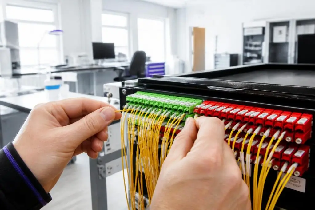 A person is working on a network distribution panel with many cables.