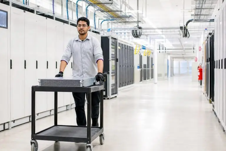 A man pushes a server on a cart through a data center.