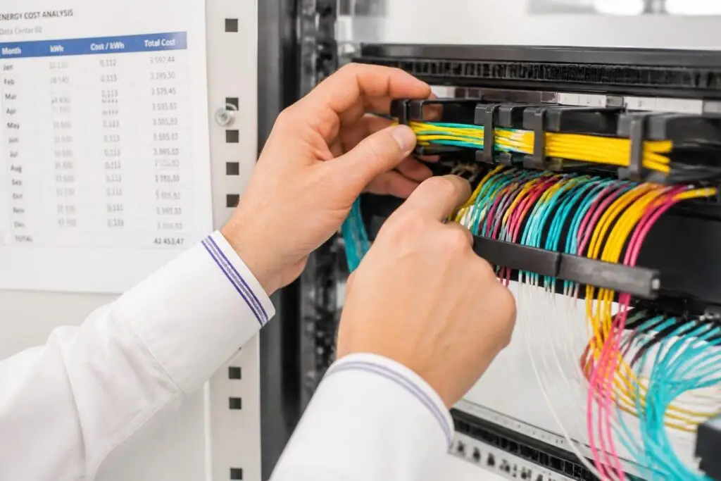 A person is working on a server rack with cables.