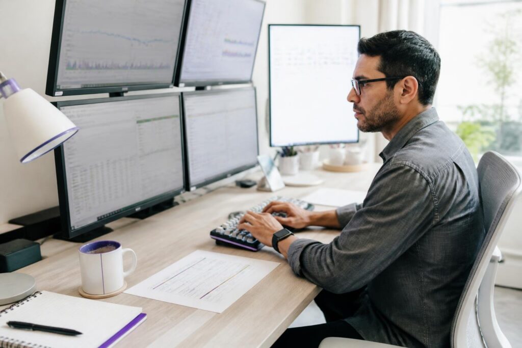 A man working at multiple monitors in an office.