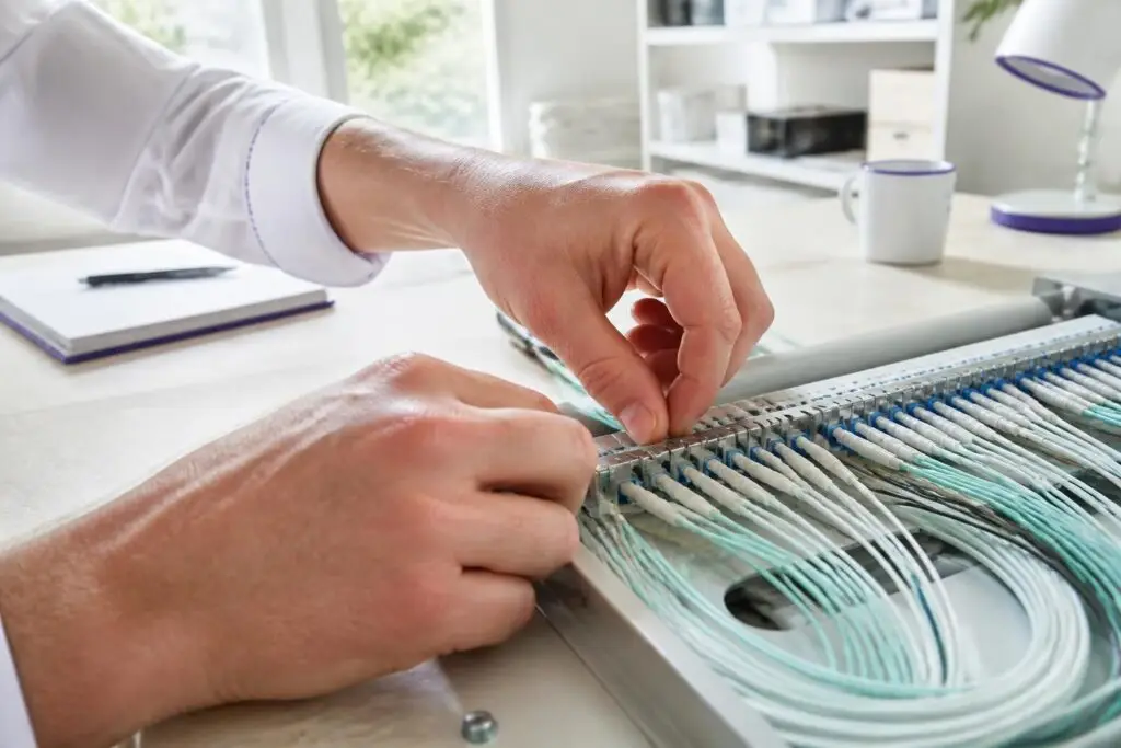 A person is working on a cable distribution panel.