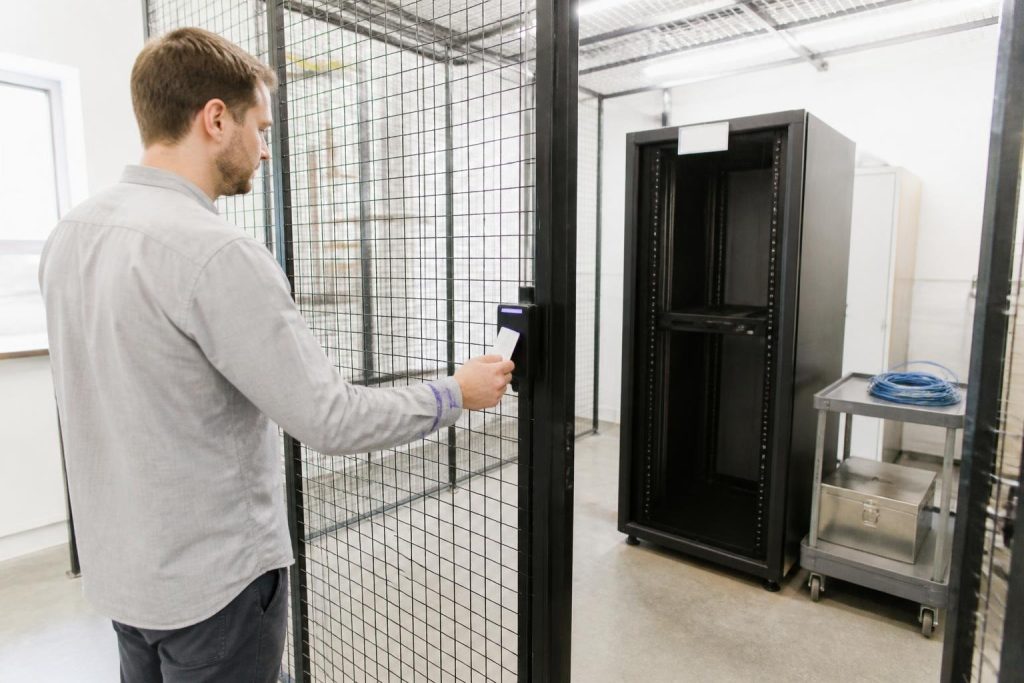A man opens a cage door to a server room using a card.