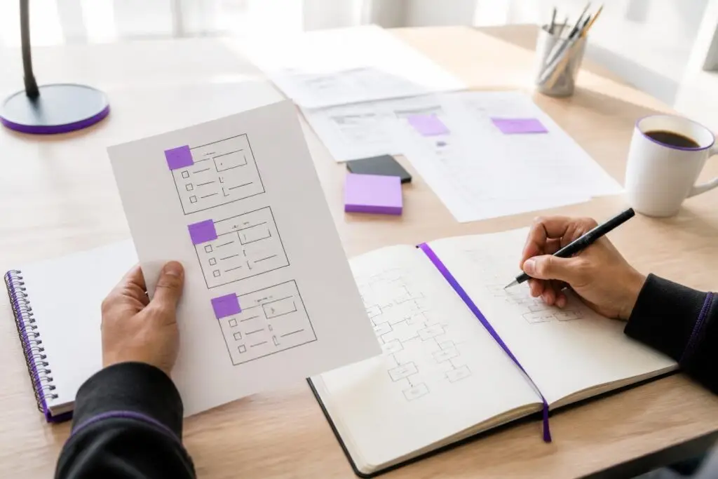 A person holds a diagram and draws in a notebook.