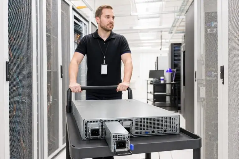 A man pushes a server on a cart through a data center.