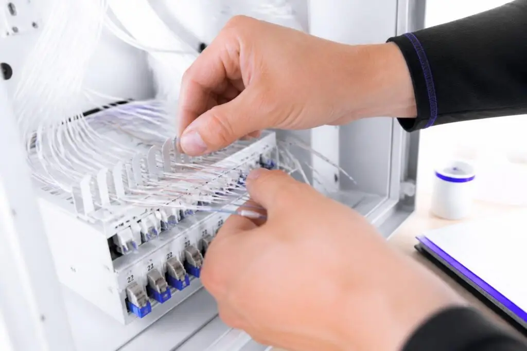 Hands working on cable connections in a distribution box.