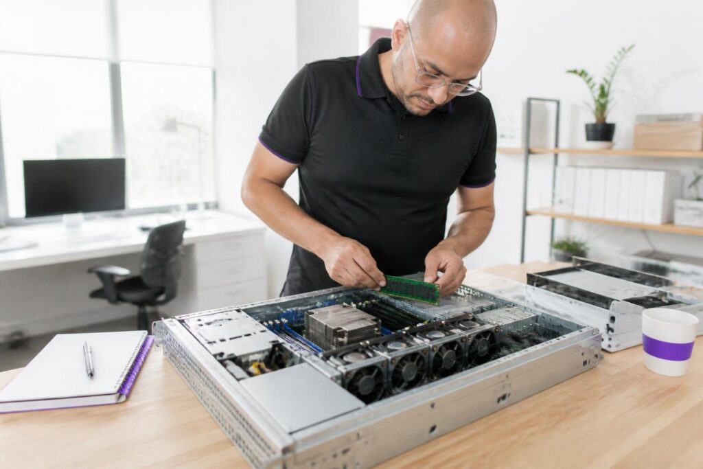 A man is working on an open server in an office.