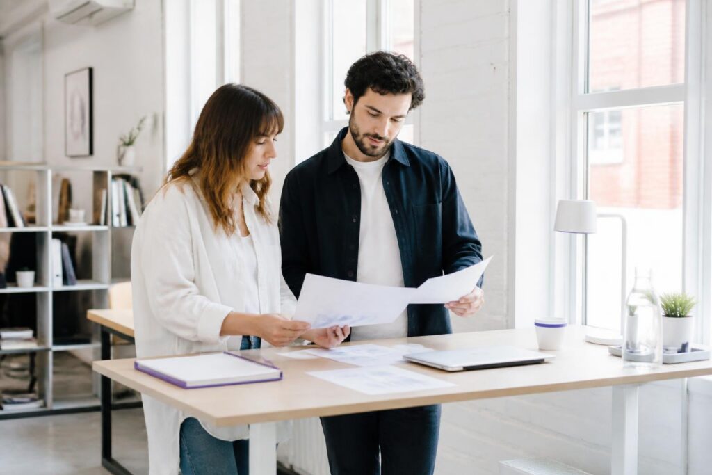 Two people standing at a table looking at documents.