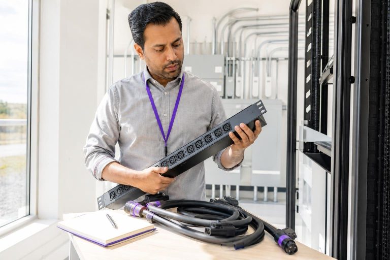A man holds a power strip in a technical room.