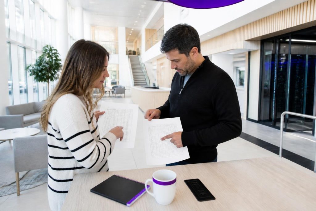 Two people discussing documents in a modern office.