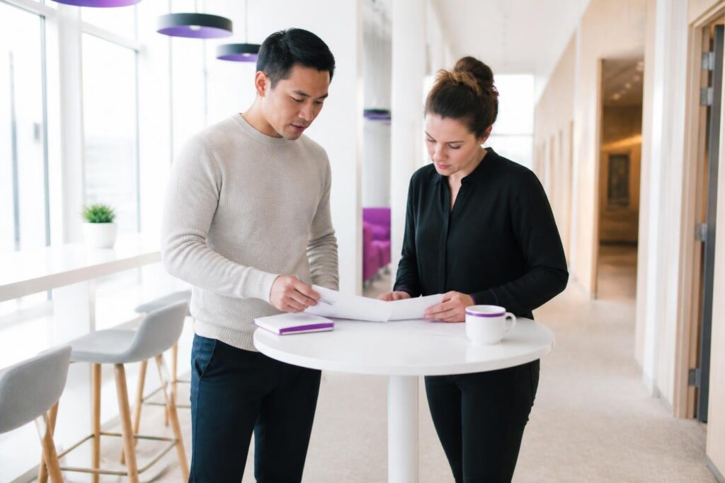 Two people standing at a table looking at documents.