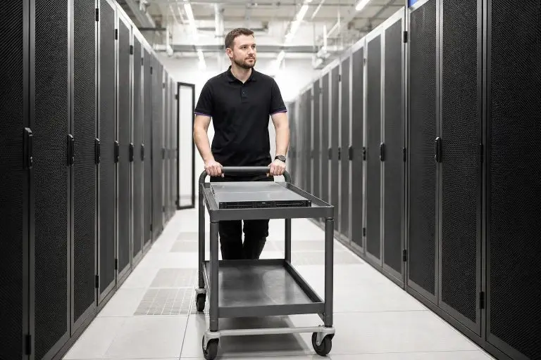 A man pushes a cart in a server room.