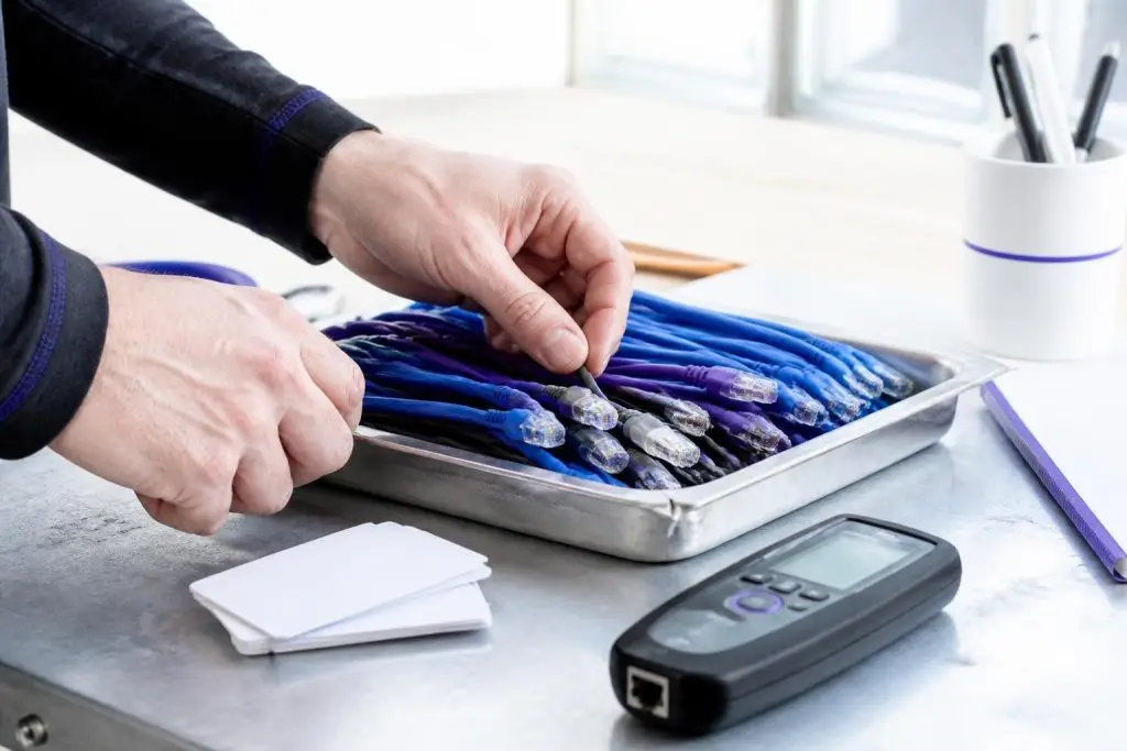 A person sorting network cables on a table with a measuring device.